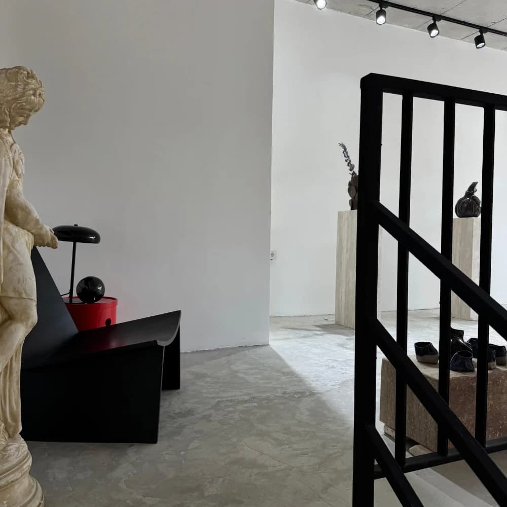 The studio: a plaster figure, a black chair and a steel staircase in daylight