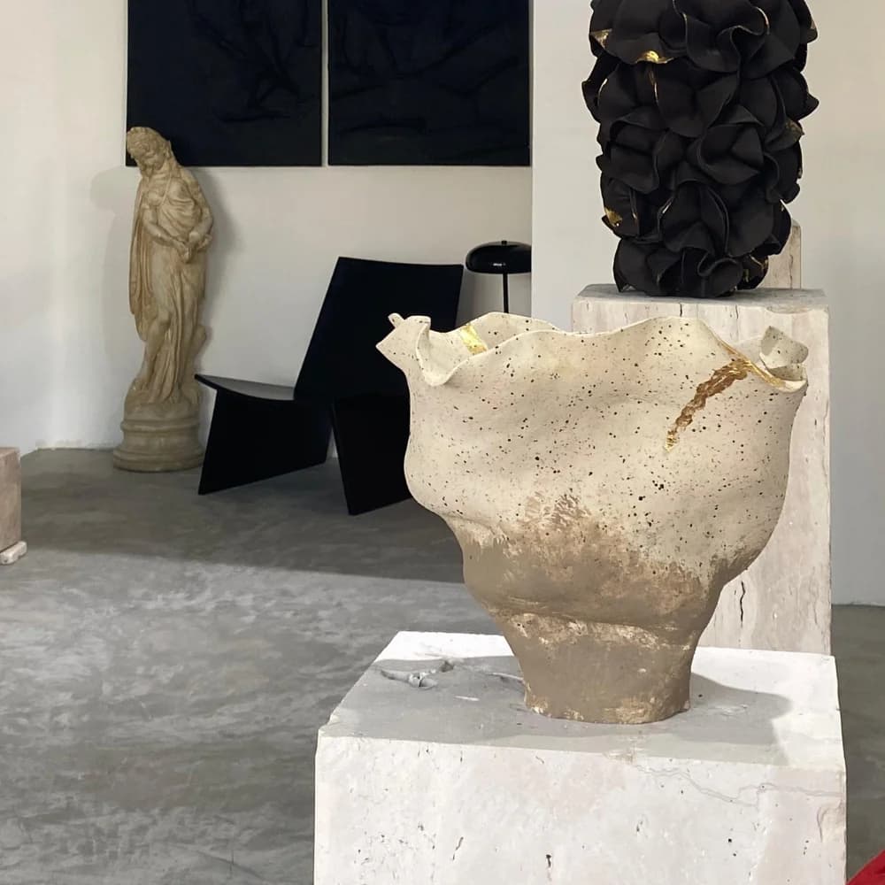 Traverten kaide üzerinde benekli, fırfırlı bir kap; arkasında siyah bir sandalye